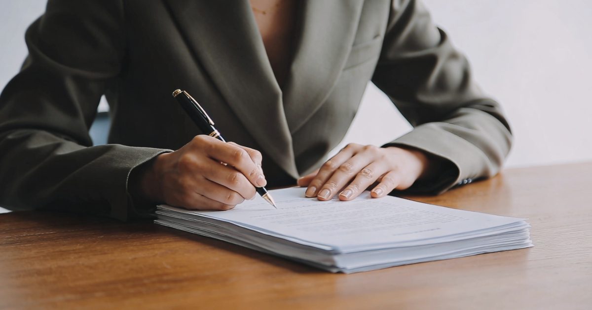 femme assise a un bureau signant des papiers