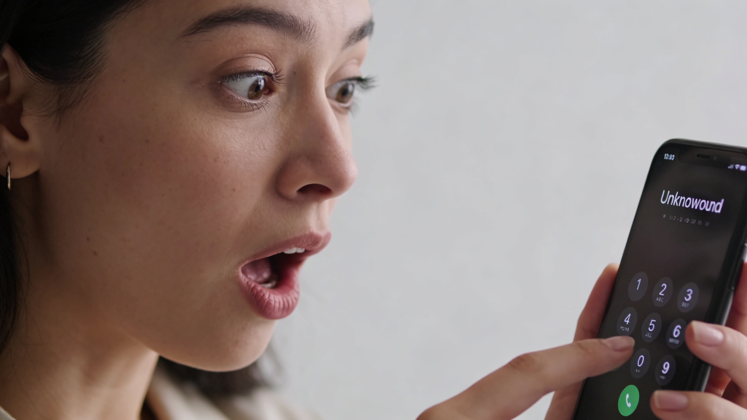 Femme surprise regardant son telephone affiche un numero inconnu