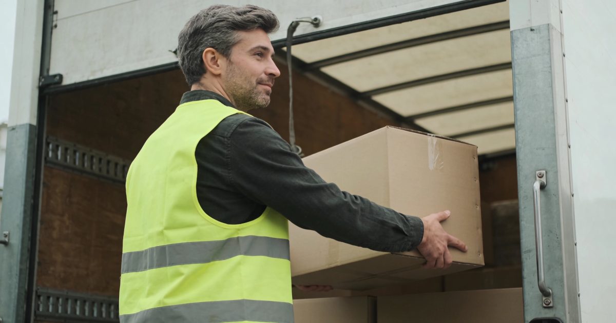 Homme en gilet fluorescent charge colis dans camion