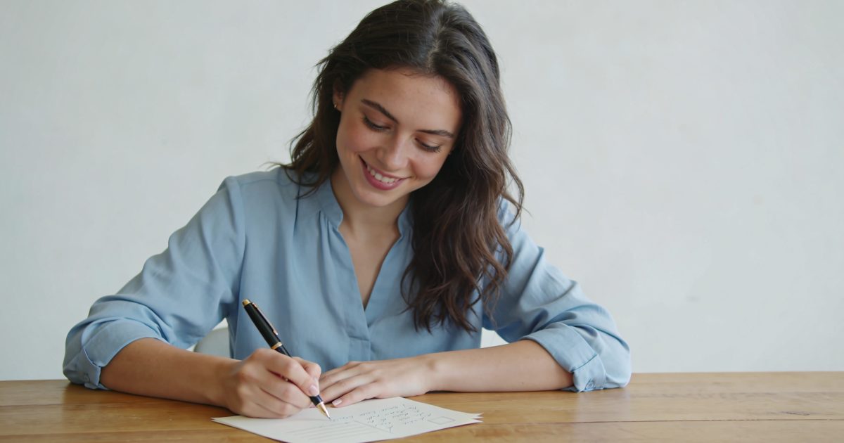 jeune animatrice souriante ecrivant une lettre manuscrite