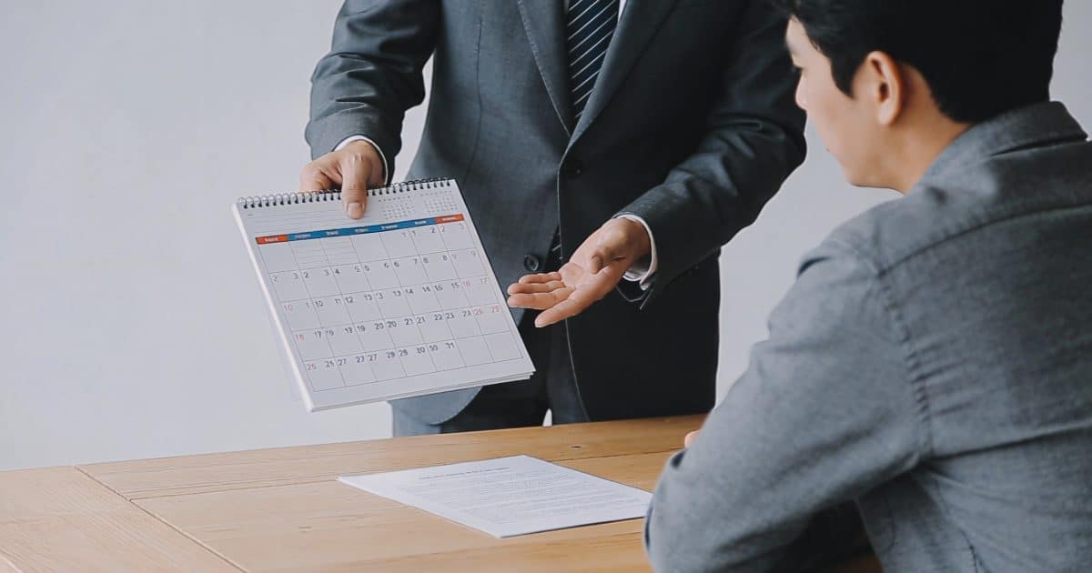 banquier montrant calendrier a cliente devant contrat