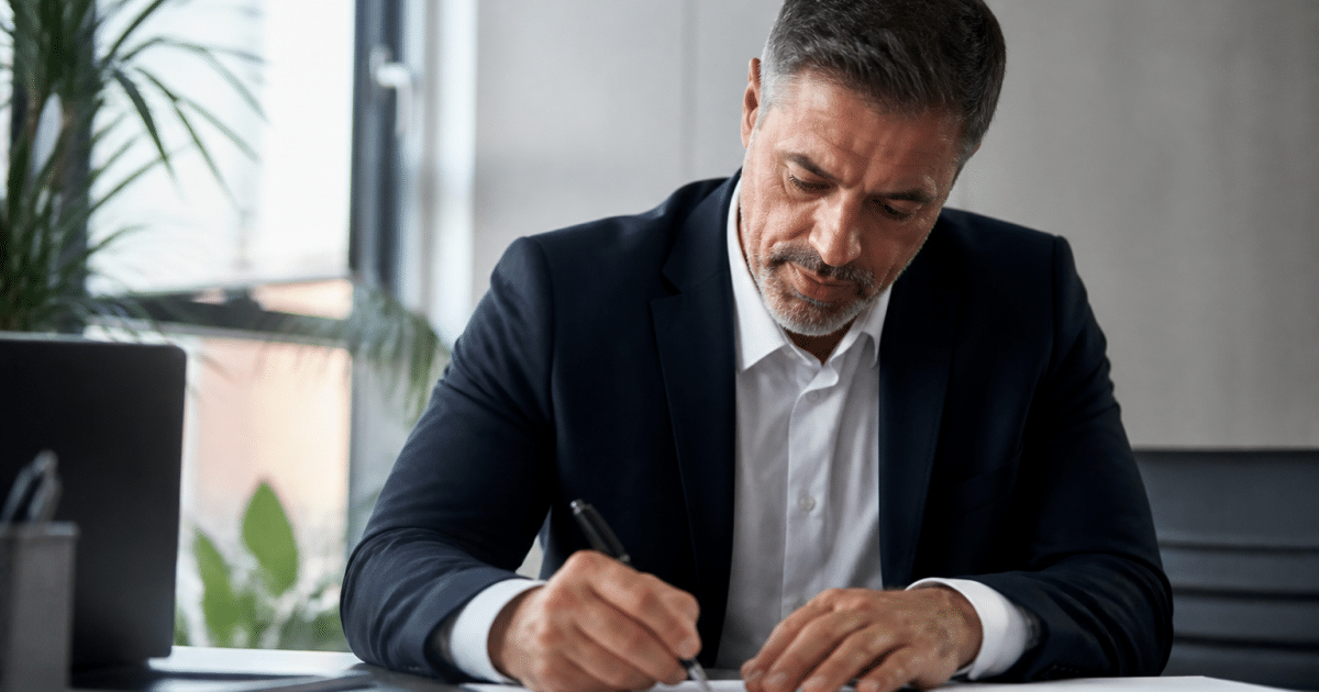 Businessman signing contract papers at office desk