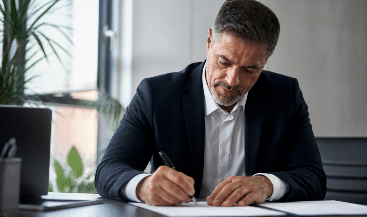 Businessman signing contract papers at office desk