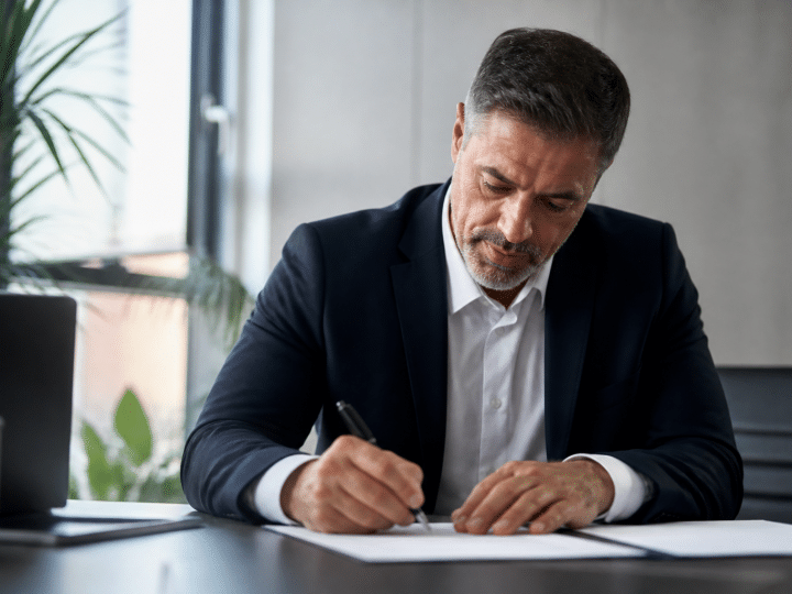 Businessman signing contract papers at office desk
