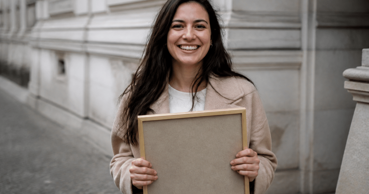 Personne tenant son diplôme encadré entre les mains, souriant