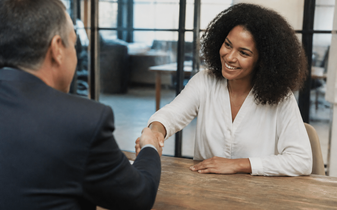 Employeur signant un contrat permanent avec un candidat souriant