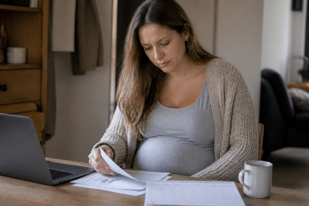 Femme enceinte consultant documents financiers avec calendrier sur bureau