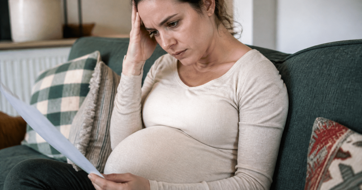 Femme enceinte assise consultant documents financiers inquiète