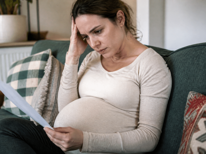 Femme enceinte assise consultant documents financiers inquiète