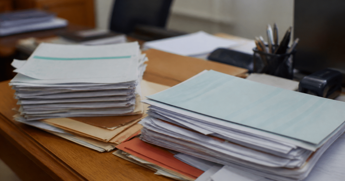 Formulaires administratifs et documents fiscaux empilés sur bureau.