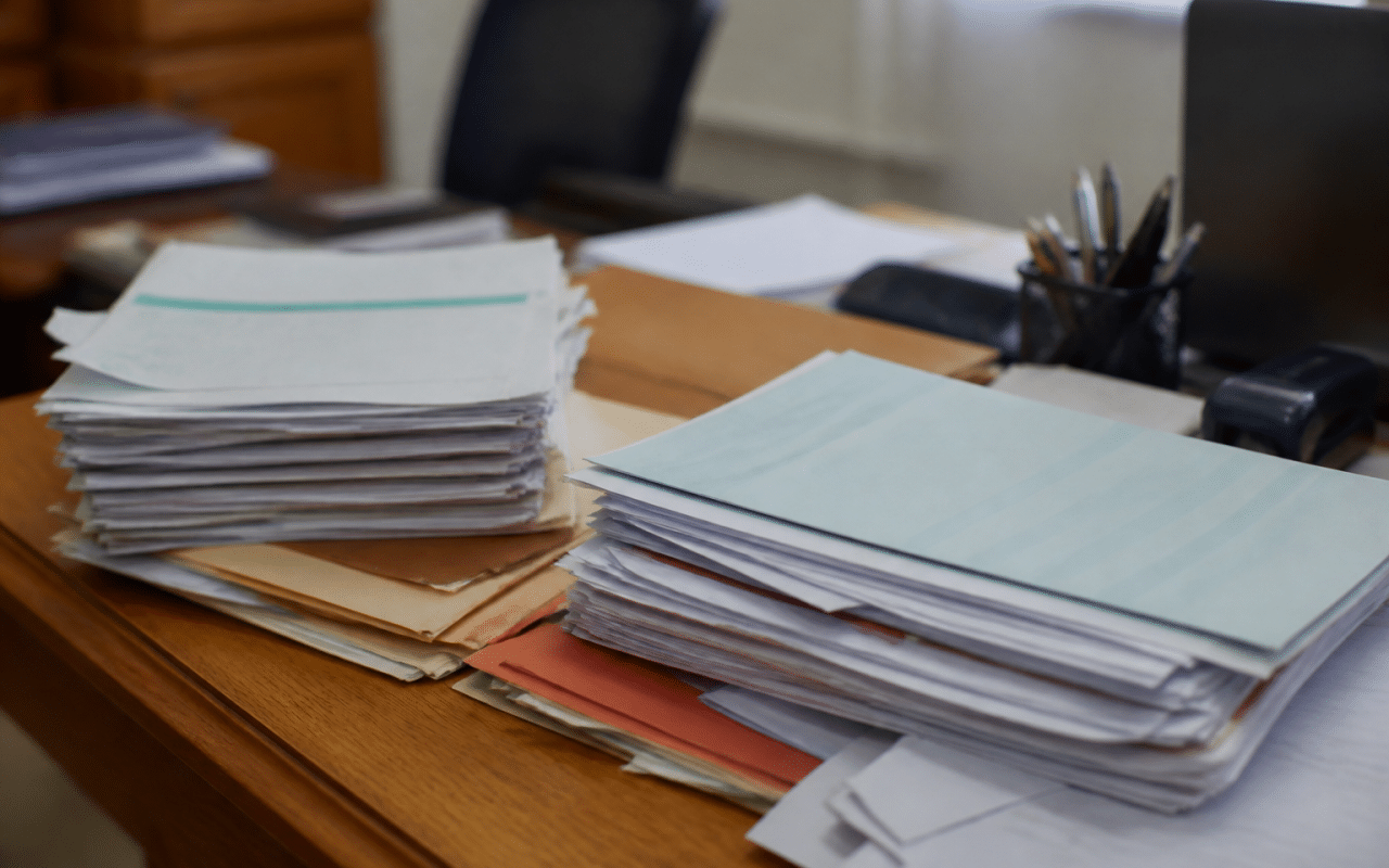 Formulaires administratifs et documents fiscaux empilés sur bureau.
