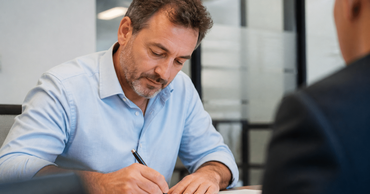 Homme age moyen signant document pret bancaire assis bureau