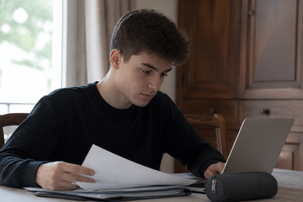 Adolescent consultant ordinateur et documents emploi simultanement