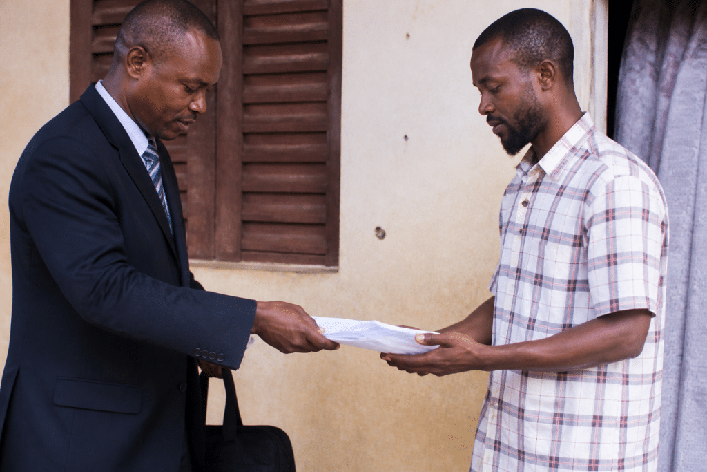 Officier en costume remettant documents officiels au debiteur