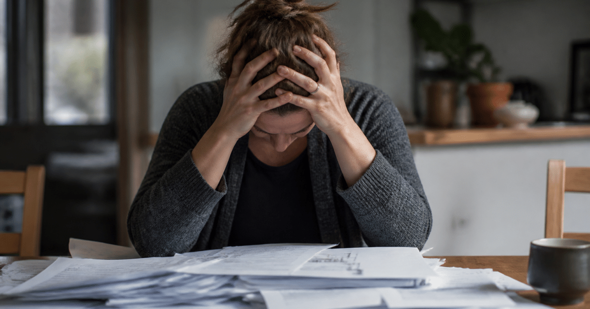 Personne accablee face a des factures et dettes empilees sur bureau