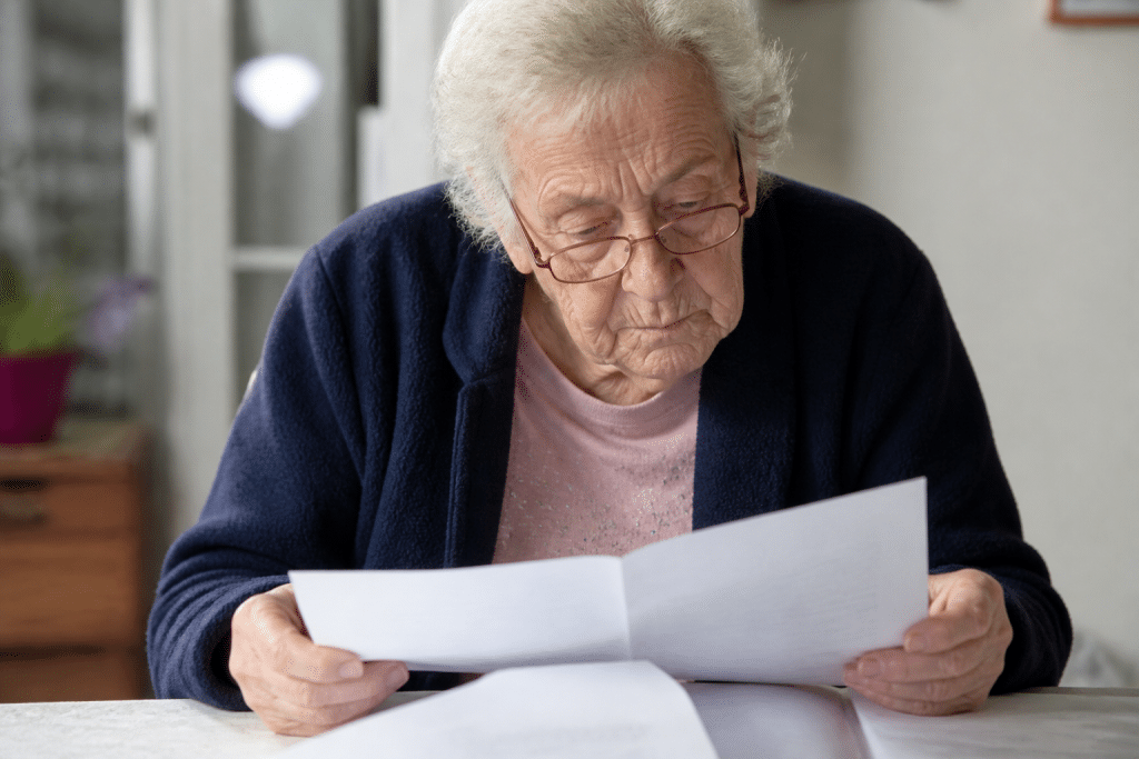 Personne agee consultant ses documents fiscaux avec lunettes.