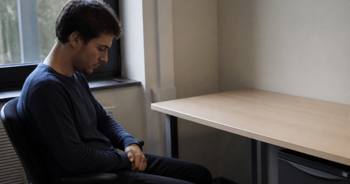 Personne assise devant un bureau vide regardant vers le bas