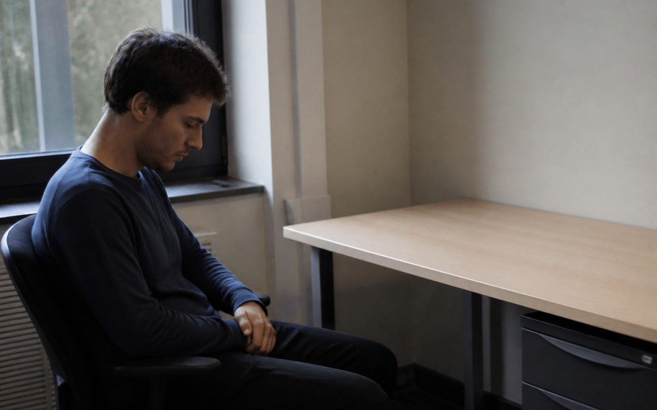 Personne assise devant un bureau vide regardant vers le bas