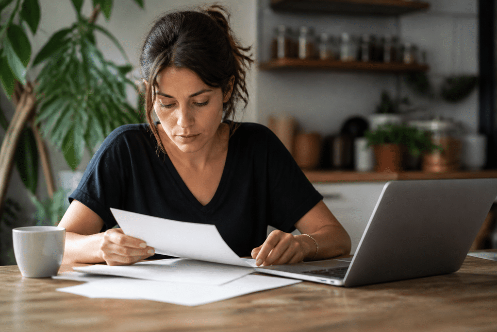Personne consultant documents papier et ordinateur portable.