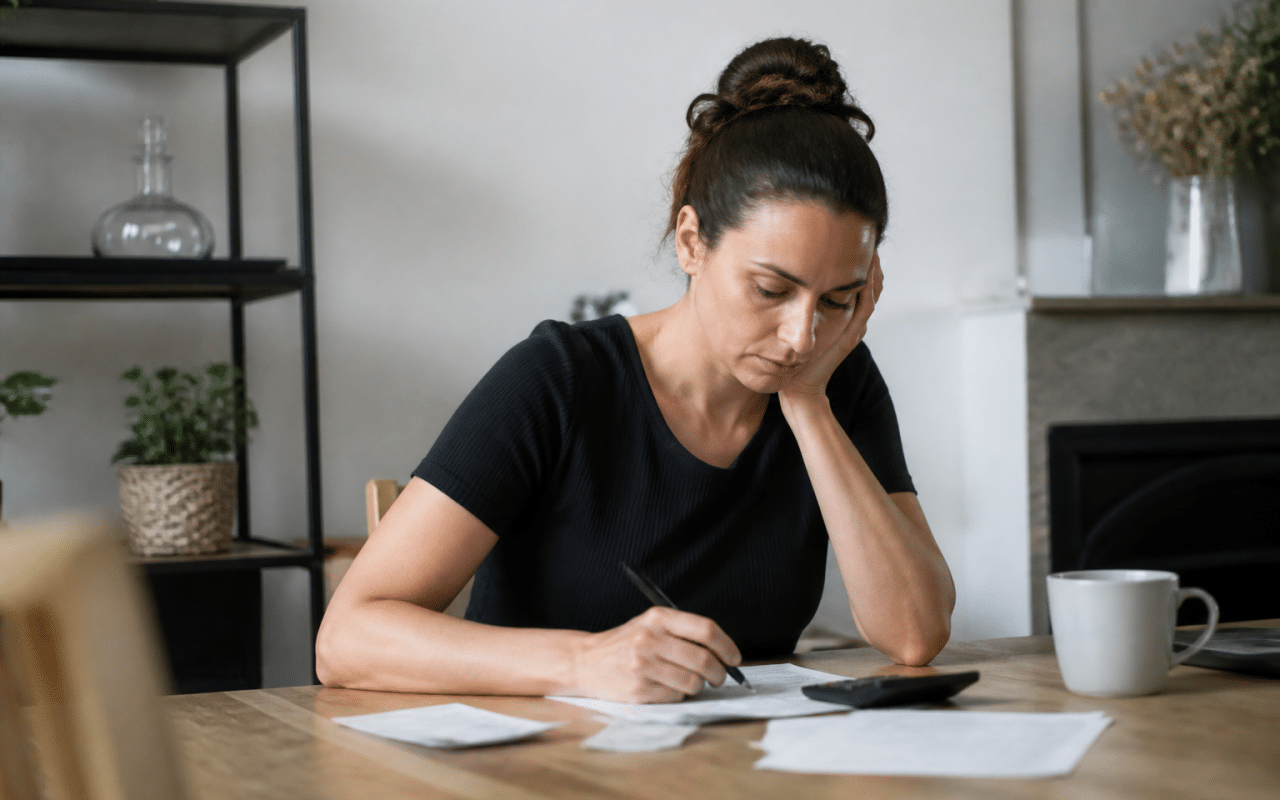 Personne seule assise a table calculant budget allocation logement