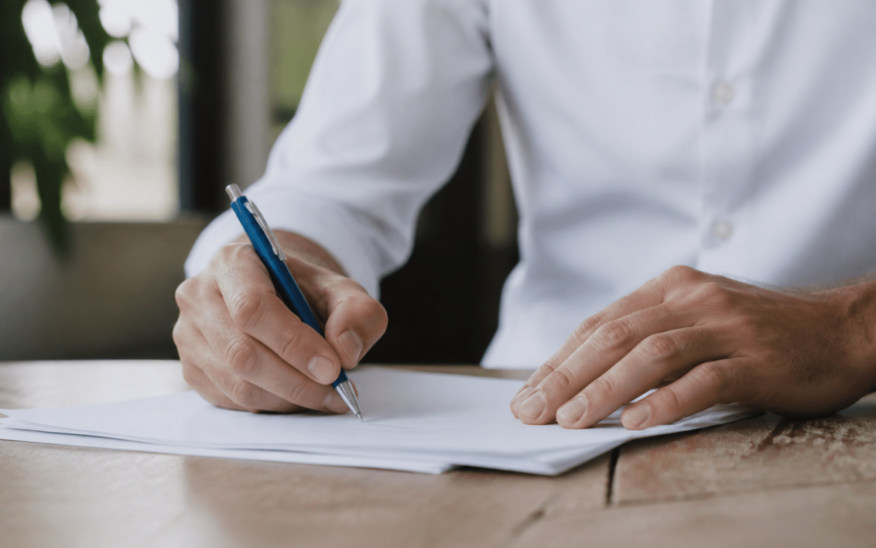 Personne signant un document commercial avec stylo bleu