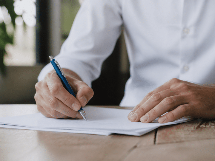 Personne signant un document commercial avec stylo bleu