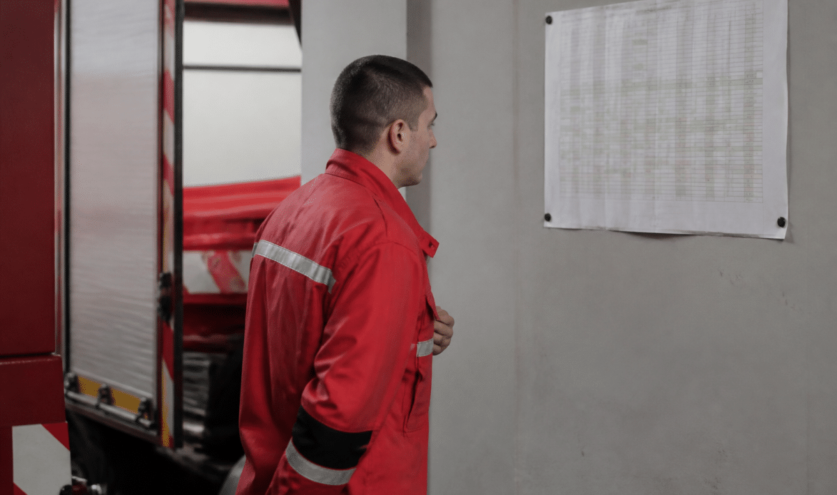 Pompier en tenue rouge consultant planning mensuel affiche