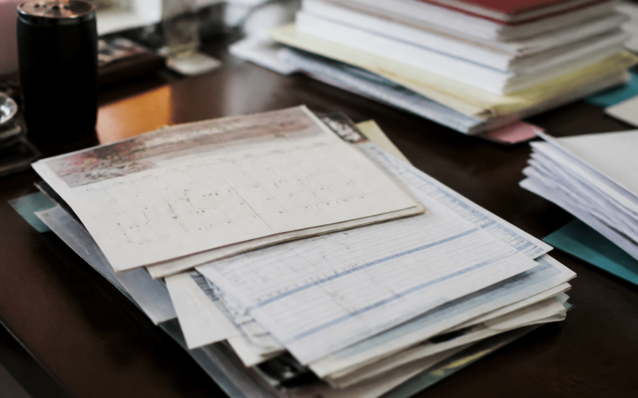 Documents administratifs empilés montrant calendrier et bulletins de paie hospitaliers