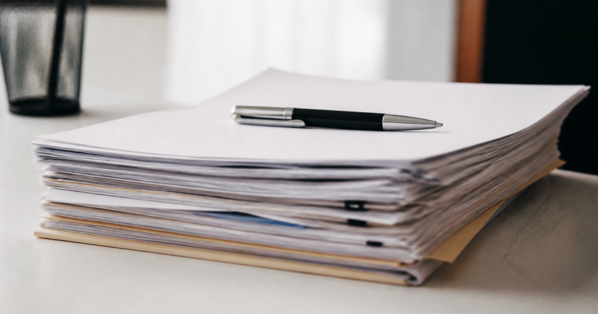Documents officiels empiles sur bureau blanc, stylo pose dessus