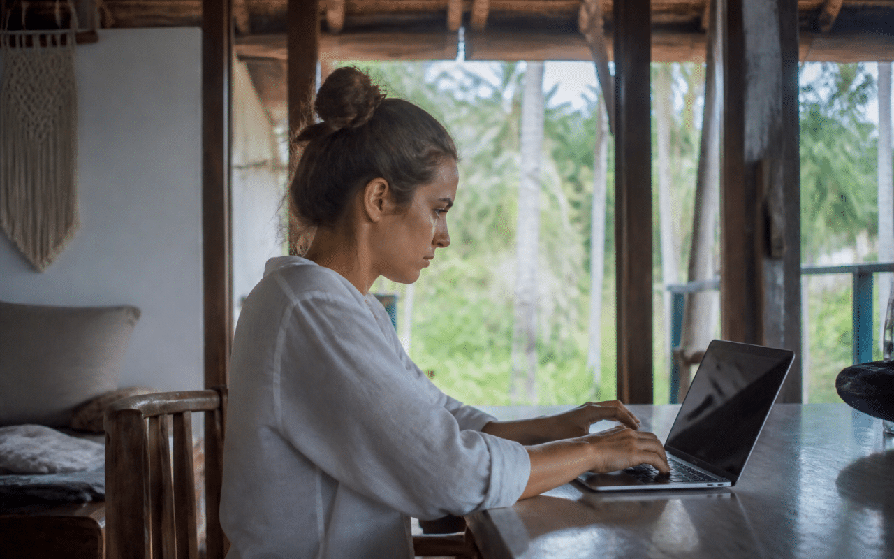 Personne assise au bureau travaillant sur ordinateur portable pendant vacances