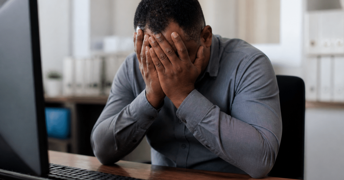 Travailleur assis tenant sa tete entre ses mains, fatigué