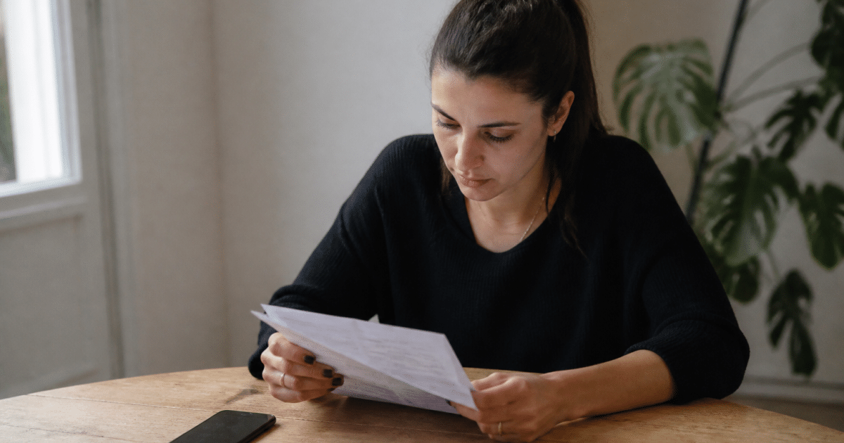 Personne consultant document bancaire sur bureau avec telephone a cote