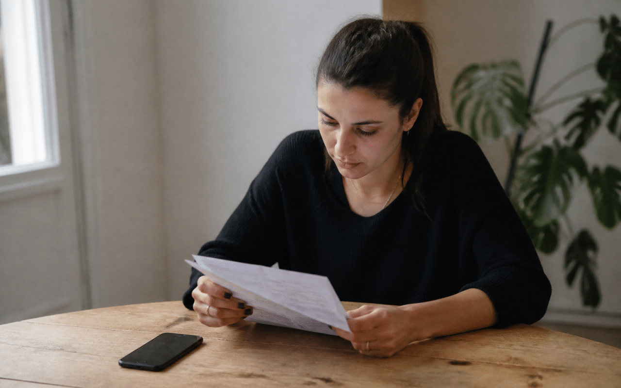 Personne consultant document bancaire sur bureau avec telephone a cote