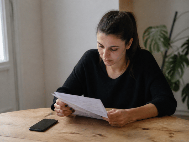 Personne consultant document bancaire sur bureau avec telephone a cote