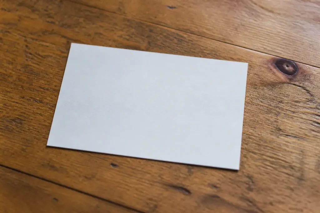 Carte postale blanche posee sur une table en bois