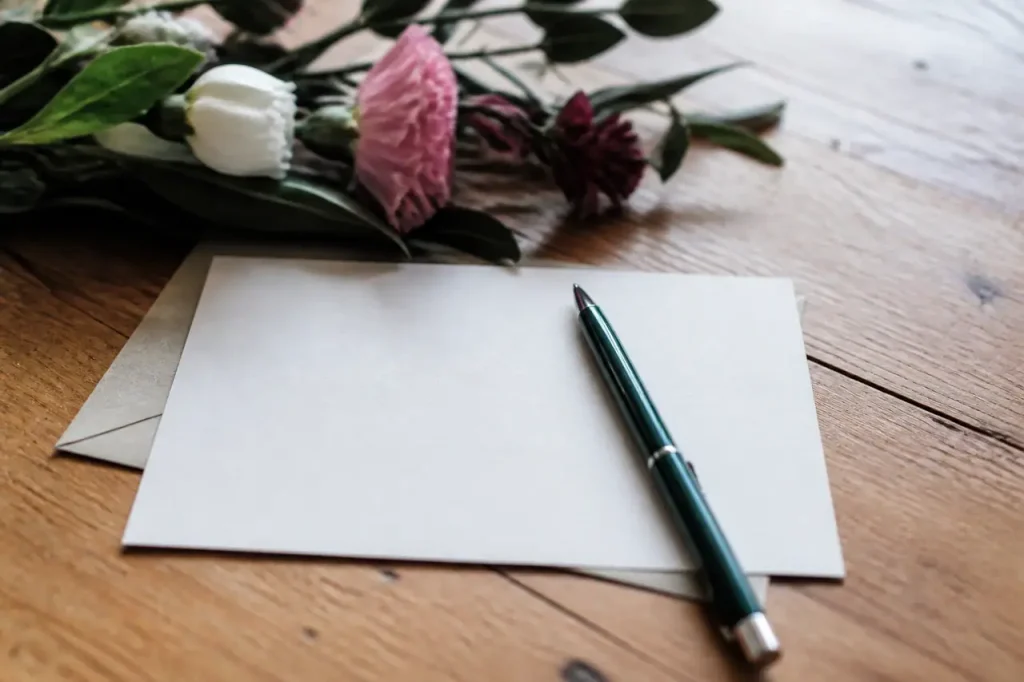 Carte de voeux, stylo et fleurs sur une table