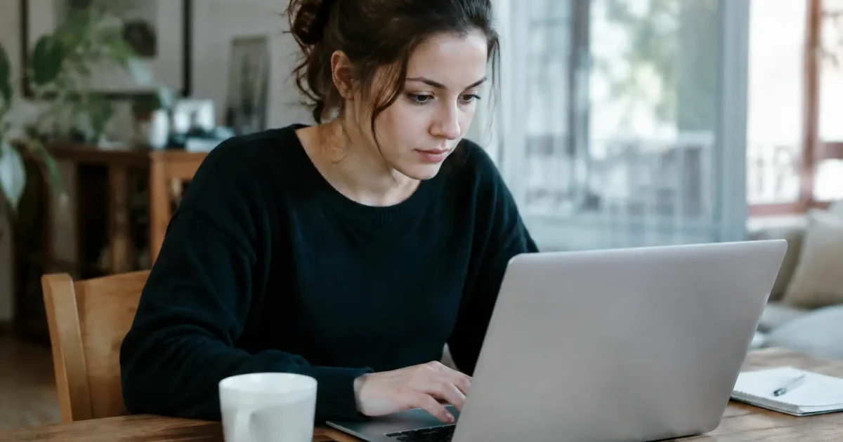 Femme assise remplissant un formulaire sur son ordinateur portable