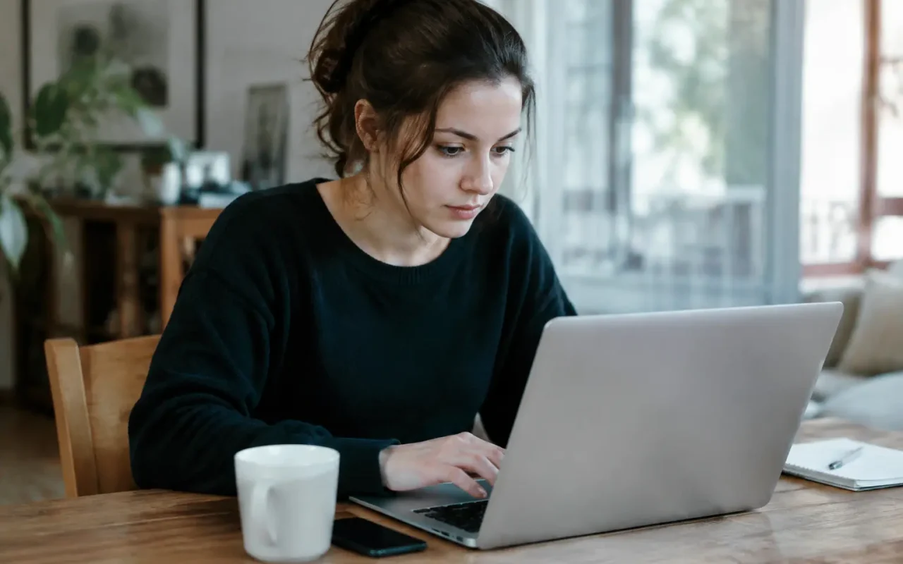 Femme assise remplissant un formulaire sur son ordinateur portable
