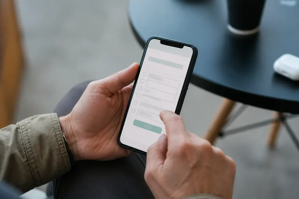 Mains tenant un smartphone affichant un formulaire en ligne