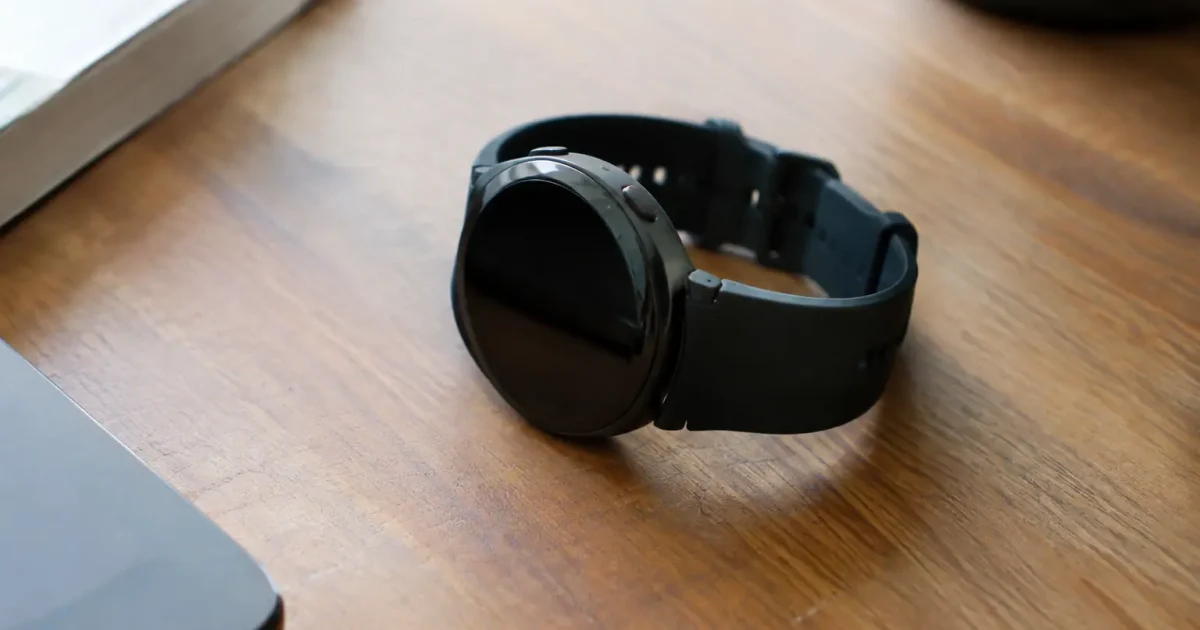 Montre connectée noire posée sur un bureau en bois