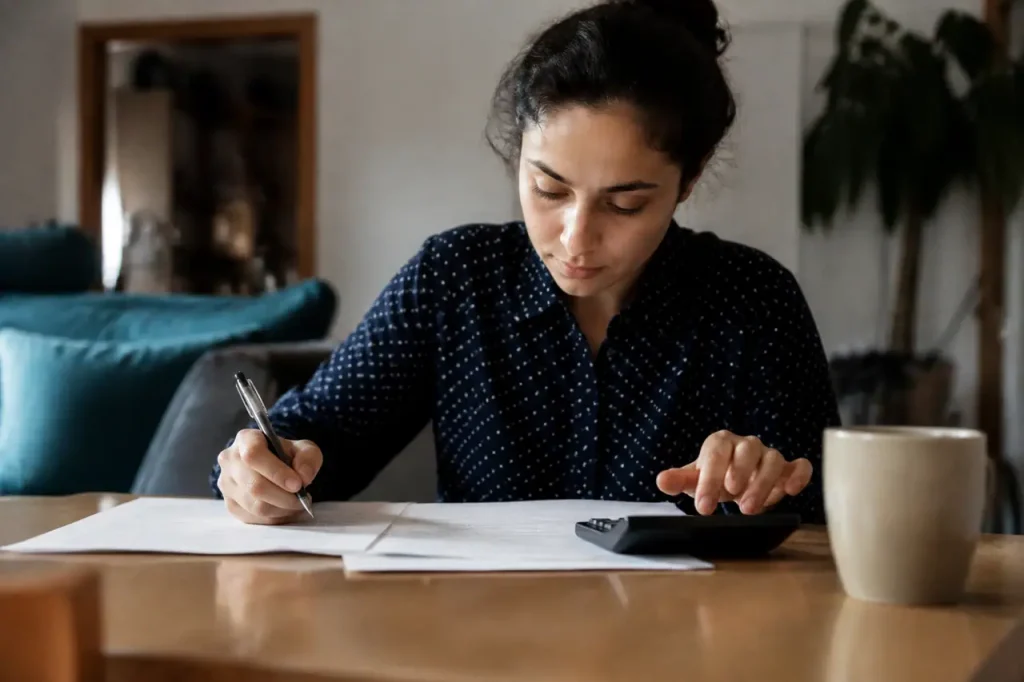 Personne remplissant un formulaire avec stylo et calculatrice