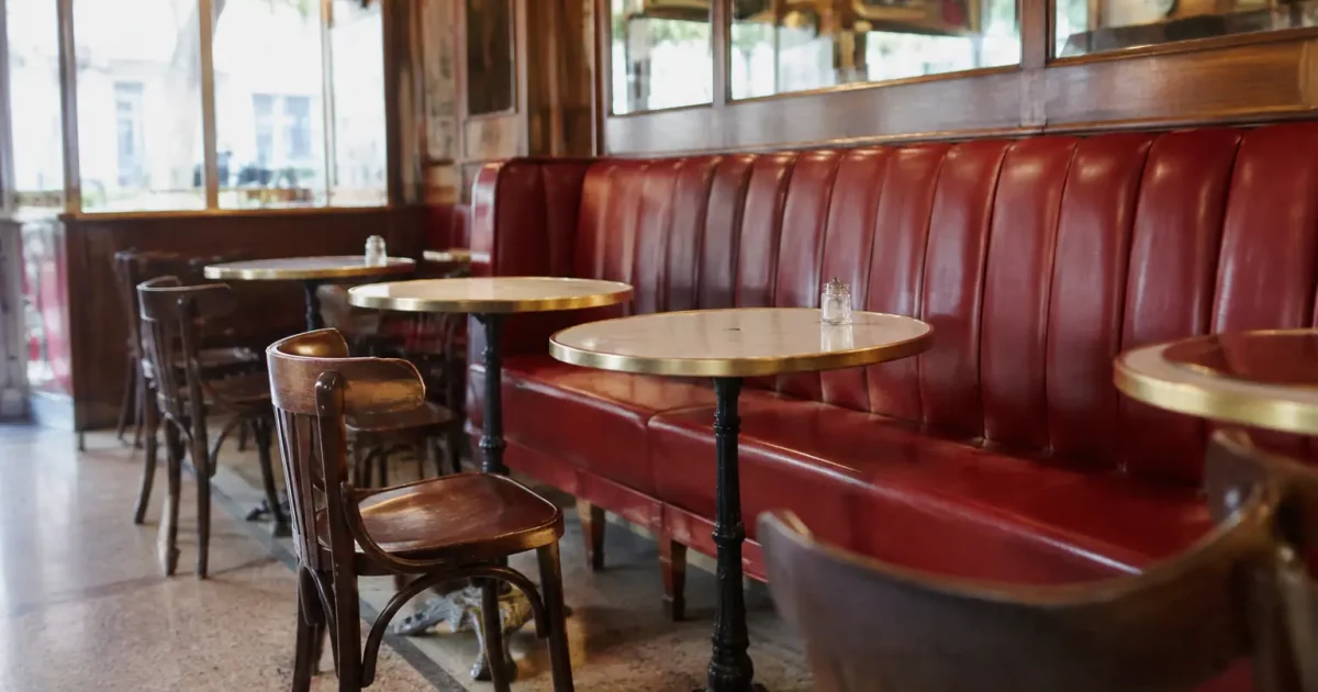 Salle de bistrot avec banquettes rouges et tables rondes