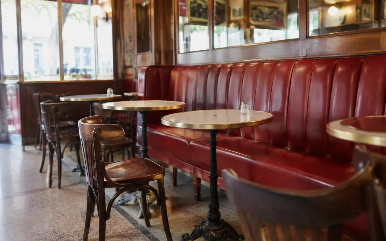 Salle de bistrot avec banquettes rouges et tables rondes
