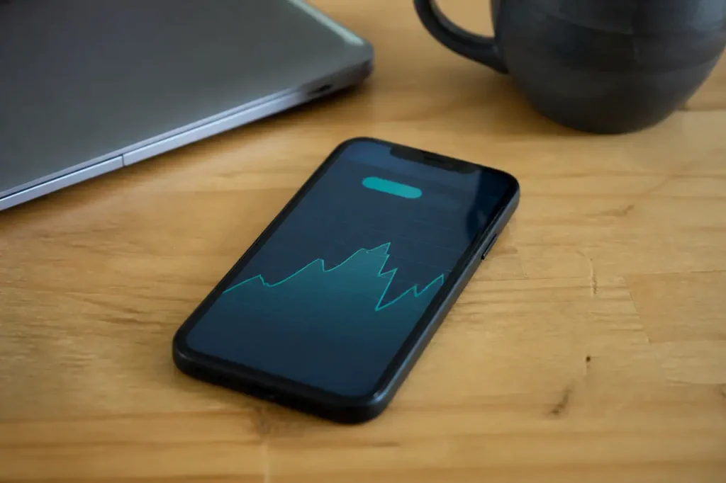 Smartphone affichant un montant mensuel estime sur un bureau