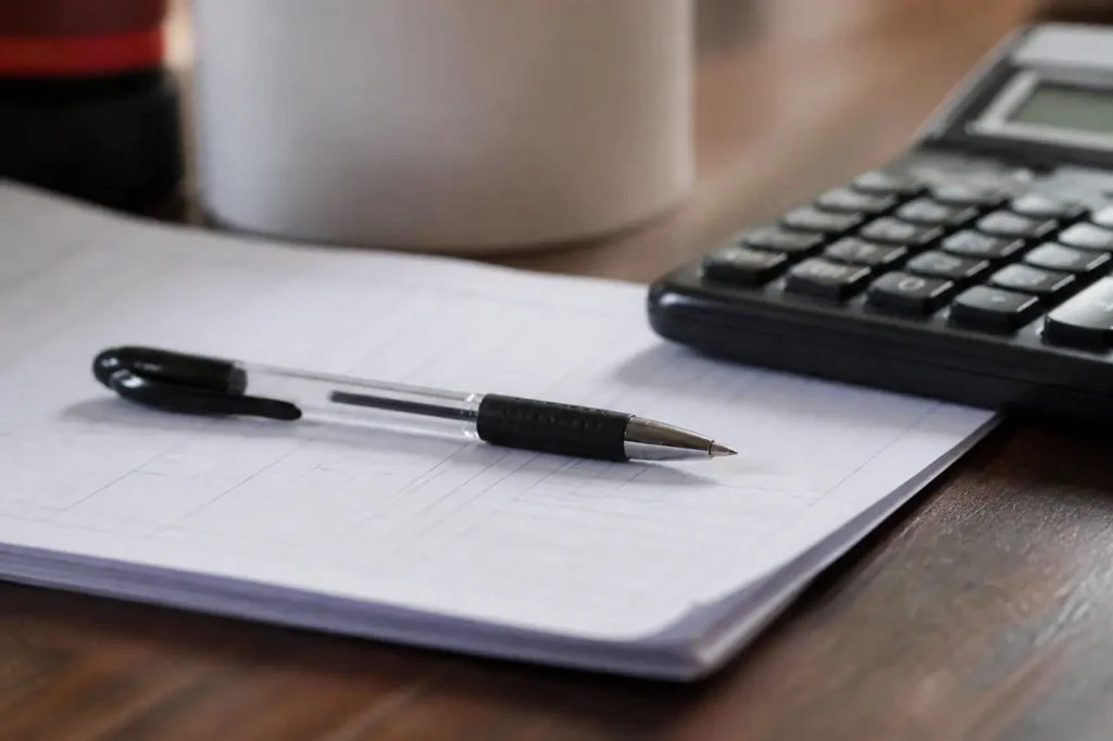 Stylo pose sur un formulaire papier et calculatrice
