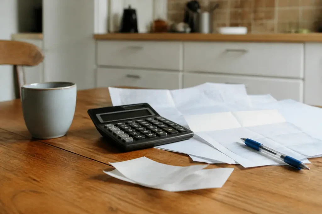Table de cuisine avec calculatrice, factures et stylo bleu